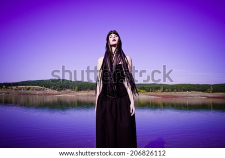 photo of the girl in black on a background of purple sky and water