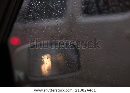 Droplets and car lights reflections through foggy car window and rear view mirror