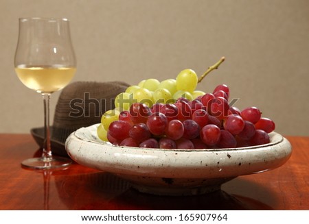 Red and green grapes with wine/A moment to savor/Red and green grapes on a ceramic plate with a glass of wine.
