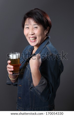 Smiling Japanese lady with beer/pretty Japanese lady with a beer/A pretty Japanese lady drinking a beer with a smile and clenched fist.