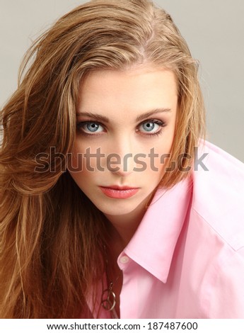 A beautiful young blonde lady/Beautiful blonde/A beautiful young blonde lady with blue eyes wearing a pink blouse. Head and shoulders portrait shot in studio.