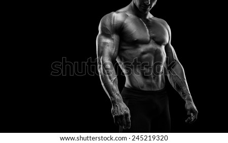 Muscular and fit young bodybuilder fitness male model posing over black background. Black and white photo with copy space