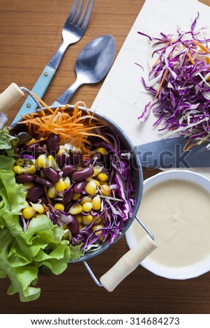 salad top view on wooden background. with carrot, corn, cabbage,violet cabbage, red beans,  Butterhead Lettuce