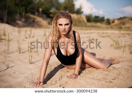 Portrait of beautiful sexy young lady laying on the sand ground on sunshine outdoors background