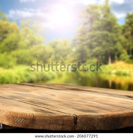 worn wooden table and river landscape of summer sun