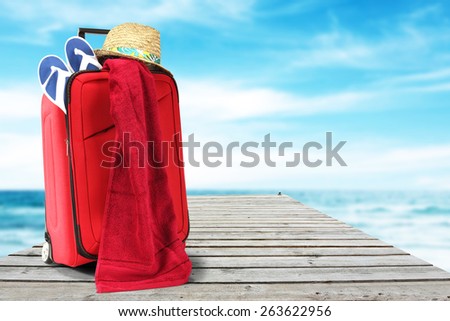 red suitcase and hat on pier