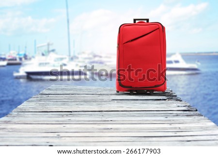 suitcase of red color and wooden pier