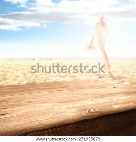 woman in bikini on hot summer sand of beach and nrown old table of free space