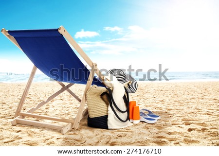landscape of ocean and beach with chair bag and hat