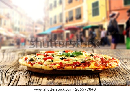 fresh warm pizza and table on street in italy