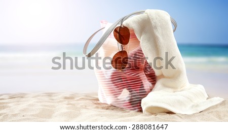 glasses bag and white towel on sand