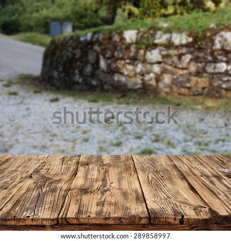 blurred background of green tuscany landscape with warm sun on sky and table of wood space