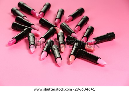 red and pink lipsticks in black tubes on pink background