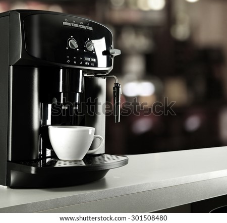 cafe interior and white cup of coffee with black coffee machine on gray top