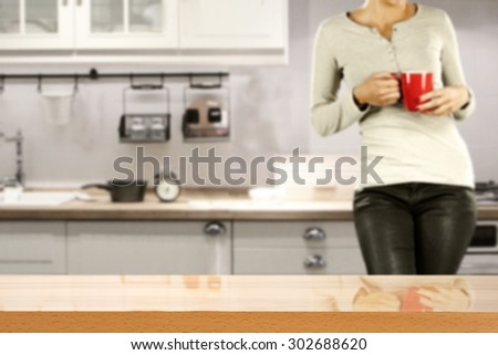gray blurred background of kitchen with young woman with red mug and  board of yellow color