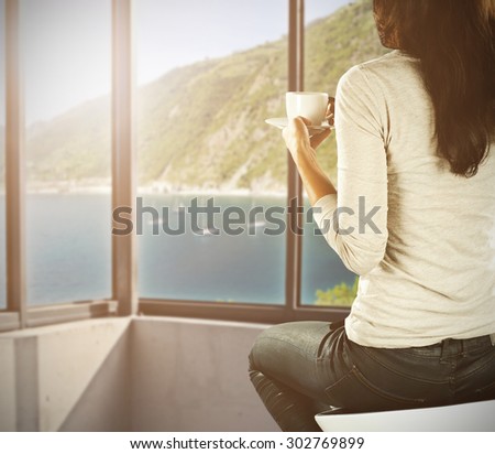 blurred background of window and landscape of sea with smell of coffee and woman on white chair