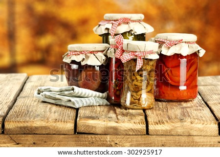 blurred background of autumn and few glasses jars on table