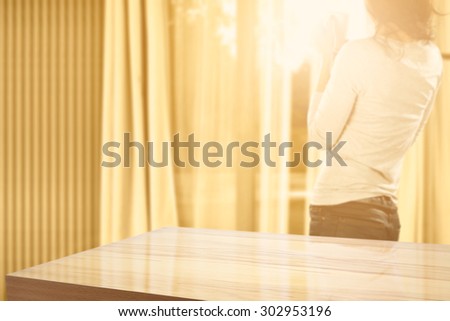 blurred yellow background of window and morning sun with young woman and desk top of yellow color