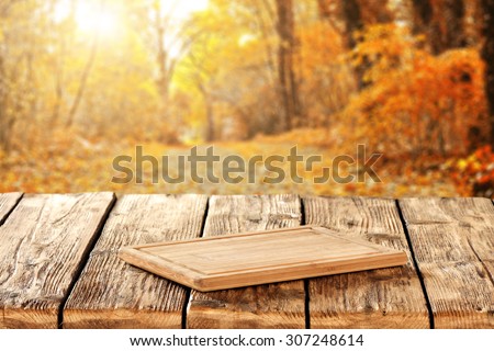 autumn landscape of golden colors of trees in park and wooden kitchen desk and sunlight
