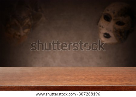 blurred background of wall with carnival mask and glasses brown desk space
