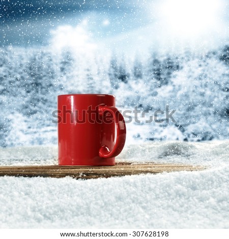 blurred background of forest in winter time and red mug