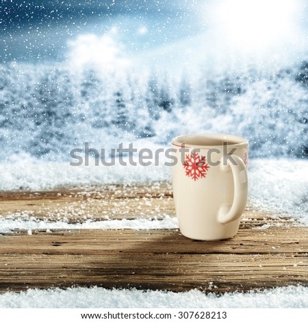 blurred background of forest in winter time and white coffee mug and xmas time