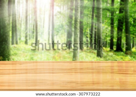 green blurred background of forest and yellow wooden glasses desk