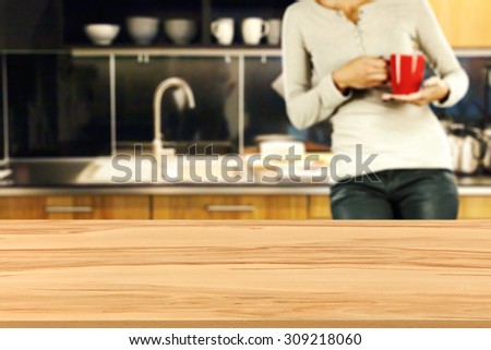 blurred background of kitchen and woman with red mug with wooden board and free place