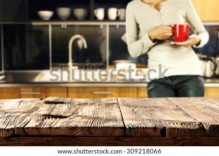 blurred background of kitchen and woman with red mug with worn old deck top place