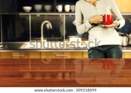 blurred background of kitchen and woman with red mug with brown glasses board