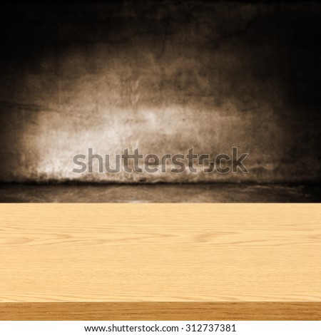 dark blurred wall of brown color and dark shadows with yellow wooden desk space