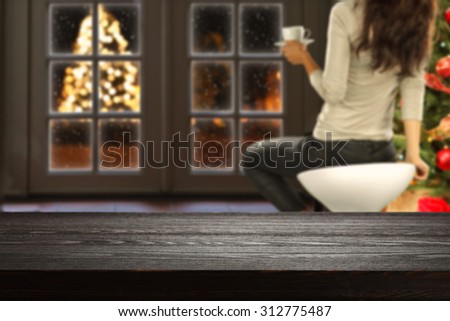 blurred background of xmas tree and window with xmas tree on street with dark desk space and free space for your decoration