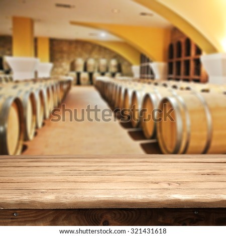 blurred interior of barrels with wine and wooden desk and old top