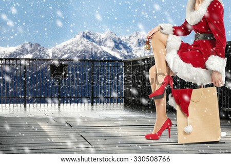 blurred background of winter terrace of snow and red heels woman legs and bag of xmas time
