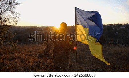 Foto Bild Soldat der ukrainischen Streitkräfte steht mit einer blau-gelben Flagge der Ukraine auf schwarzem Hintergrund