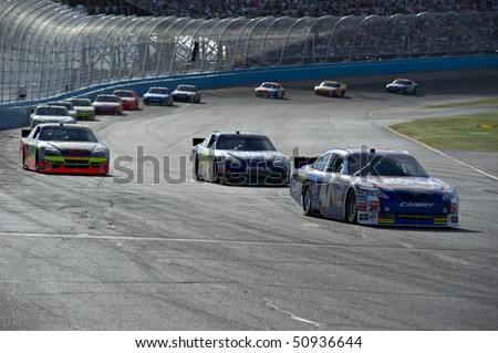 AVONDALE, AZ - APRIL 10: Marcos Ambrose (#47) leads a group of cars out of turn two at the Subway Fresh Fit 600 NASCAR Sprint Cup race on April 10, 2010 in Avondale, AZ.