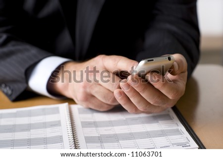 Businessman working on his cell phone.  Shot with shallow depth of field and studio lighting.