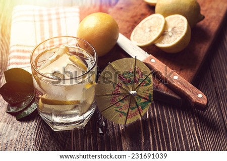 glass of water with ice and lemon on wooden table