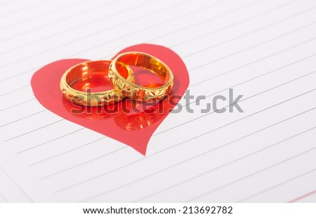 two of golden ring on red heart sticker on note book