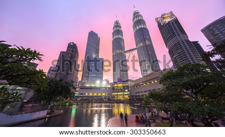 KUALA LUMPUR, MALAYSIA - AUGUST 1, 2015: Water Fountain at Suria KLCC with Petronas Towers and Office Buildings at Blue Hour sunset at Night. It's a popular shopping attraction to locals and tourists.