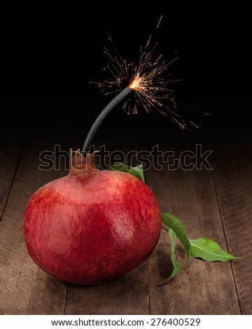 Red pomegranate with sparkler on dark wooden background. Vitamin Bomb Concept.