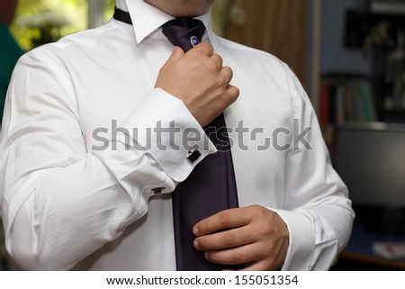 Closeup of  groom fixing his tie