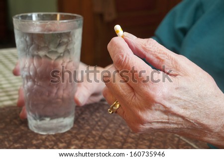 An elderly woman about to take a pill.