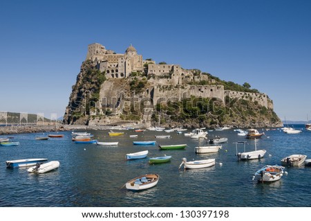 Aragonese castle in Ischia, a little island in the bay of Naples, Italy. Many little boats moored in the cove in front of it