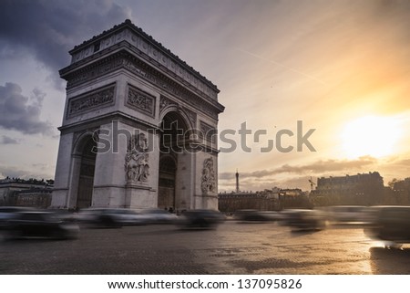 The Arch of Triumph and cars running on Place de l\'Etoile at sunset in Paris, France