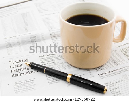 Morning coffee and pen on a morning paper business news