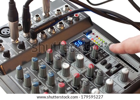 Sound director\'s finger moving the volume controller of a mixing console