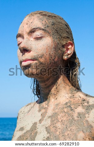Young beautiful woman getting a body mud therapy
