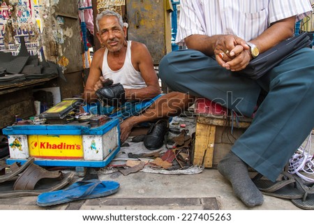 KOLKATA, INDIA - MARCH 14: Unidentified shoe shiner does his job at street of Kolkata on March 14, 2013. Lots of people make their living by doing this job in India.