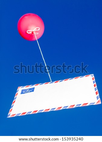 red balloon attached to an airmail envelope by a string against a bright blue sky. communication concept
